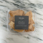 A box of The Mill's Sea Salt Sourdough Crackers shown on a marble table top. 